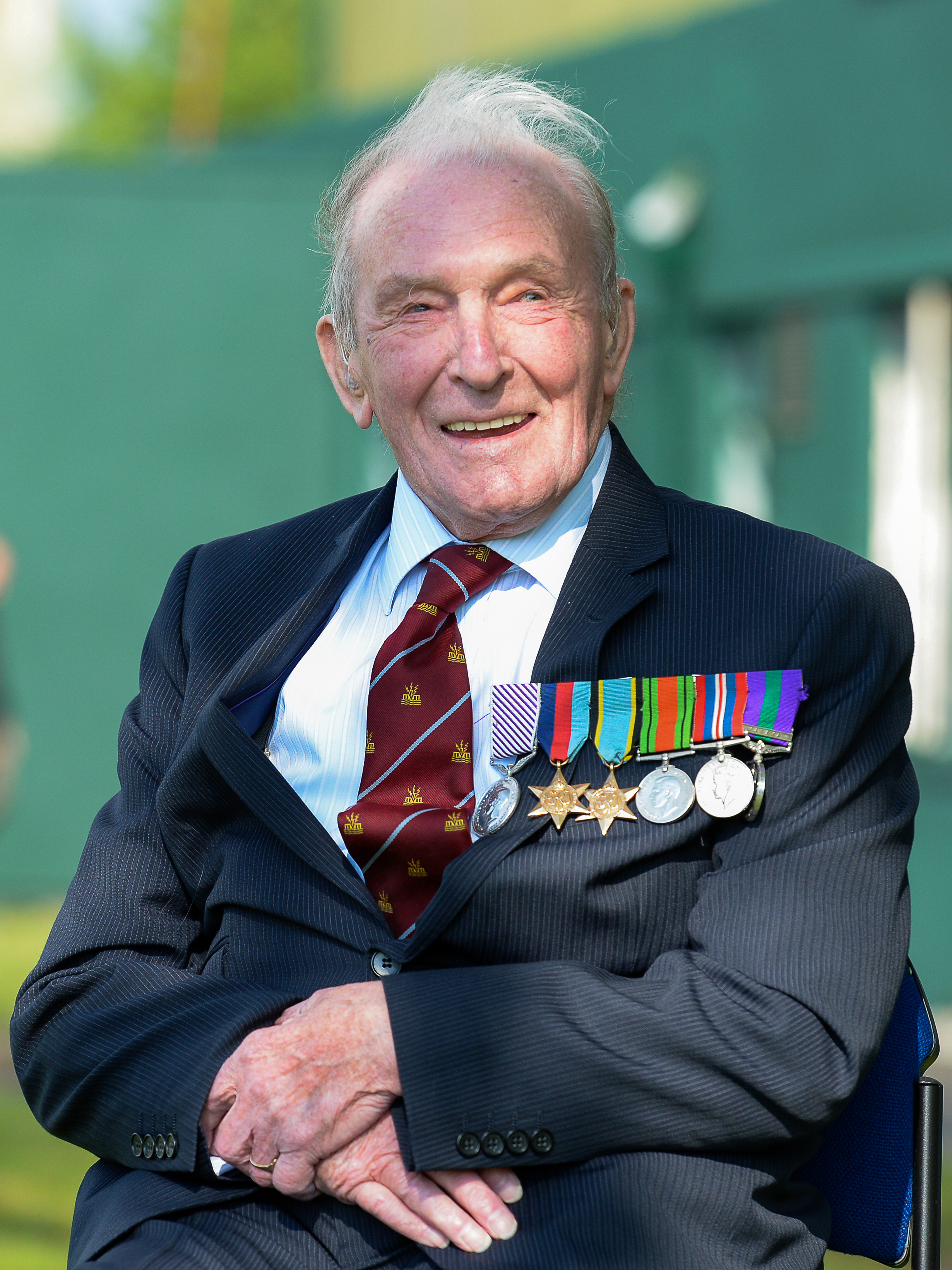 Image shows RAF Veteran wearing his medals and sitting in a chair,